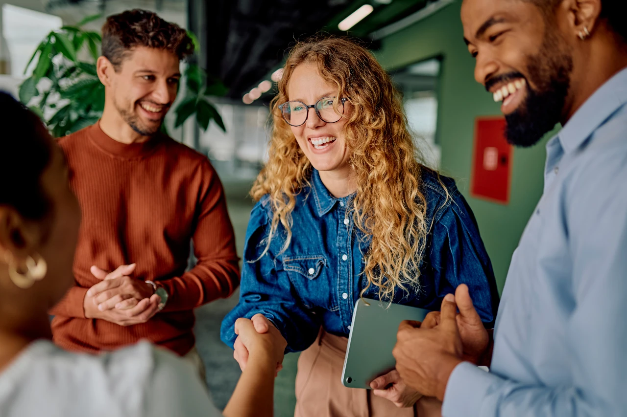 Diverse team of three professionals smiling during a collaborative hiring meeting in a modern office